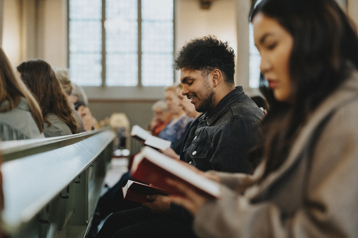 Churchgoers sit in a pew.